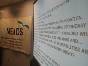 To the left is an image of a white banner with the NEADS logo and text describing disability - Image depicting conference banner at the Breaking it Down Events.